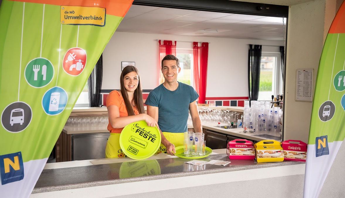 zwei lächelnde Buffett-Mitarbeitende präsentieren die Give-Aways und Leihangebote von Sauberhafte Feste